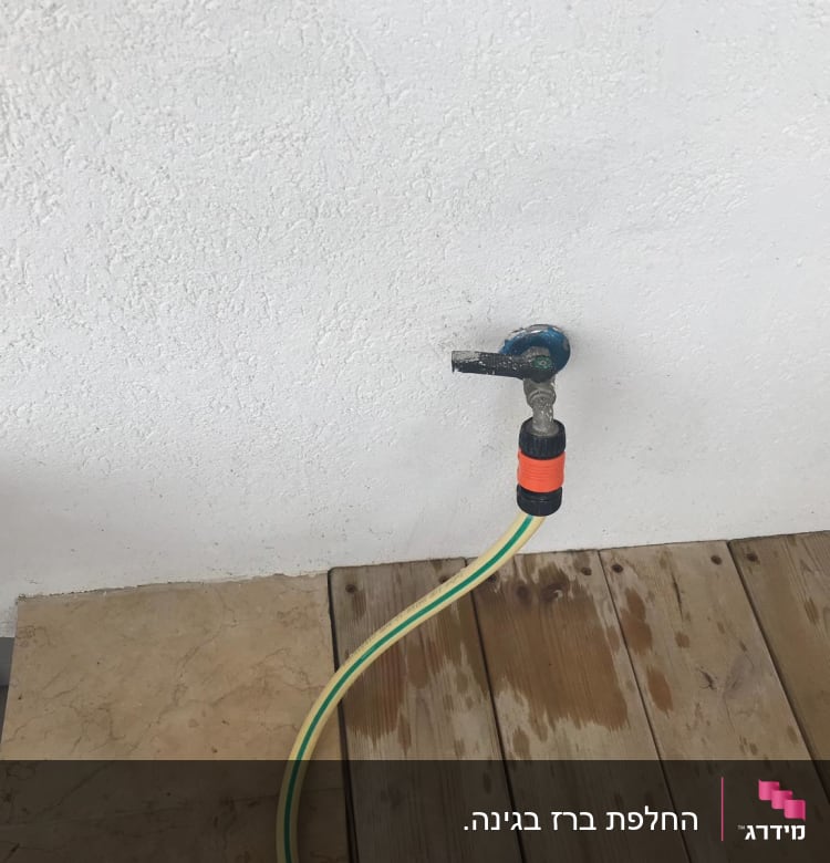 ברז מים עם צינור מחובר על קיר לבן